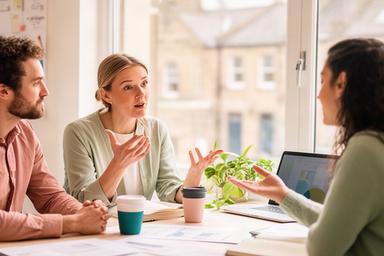 Social enterprise mentor speaking with two founders beside a window in a South Yorkshire workspace
